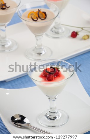 Closeup of Strawberry Panna Cotta Dessert garnished with Alpine strawberries, and chocolate shavings.