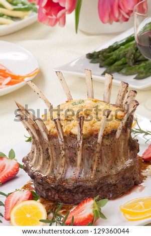 Crown roast of lamb with apple rosemary stuffing. Garnished with fresh strawberry, lemon, and rosemary twigs. Side dishes - asparagus, glazed carrots, and beans.