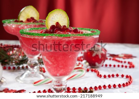 Two frozen pomegranate margaritas cocktails on Christmas decorated holiday table with Christmas ornaments. Holiday cocktails series.