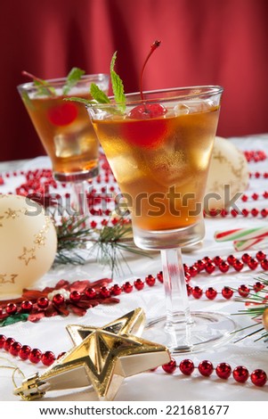 Glasses of Mint Manhattan cocktails surrounded with Christmas ornaments and decorations. Holiday cocktails series.