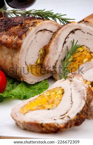 Dried apricots, pistachios, and rosemary staffed pork loin roulade served with salad, tomatoes and glass of red wine.