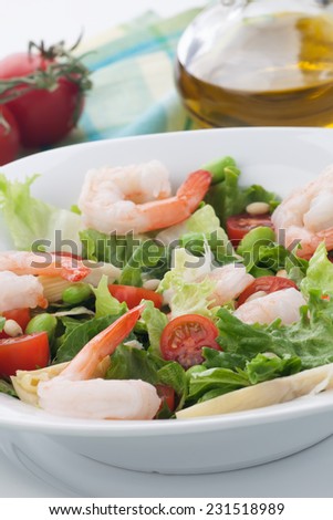 Plate of Italian shrimp salad with shrimp, tomatoes, artishocke hearts, Romane lettuce leaves, fava beans, and pine nuts. Olive oil.
