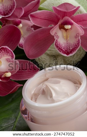 Dark pink blooming Cymbidium orchid flowers and moisturizing face cream for everyday.