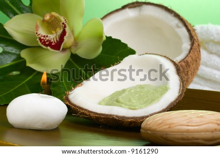 Avocado coconut scrub in coconut shell, orchid flower (Cymbidium sp.), tropical plant, soap and aroma candle. Suited for relaxing and health commercials