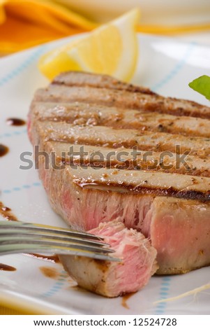 Closeup of juicy delicious Citrus-peppercorn-spiked grilled tuna steak with grilled vegetables. Shallow DOF