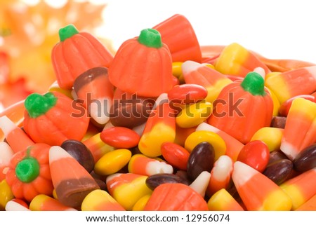 Closeup of pumpkin filled with delicious Halloween candy over fall leaves background