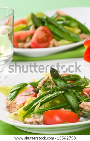 Two plates of asparagus, snow pea and tomato salad with ginger dressing. Glass of white wine and spring tulip