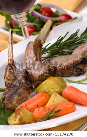 Lamb chops (ribs) with Rosemary garlic dressing, garnished with baby carrots, potatoes and rosemary sprigs. Dinner settings.