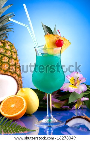 Blue Hawaiian cocktail surrounded by tropical fruits. Rum, pineapple juice, coconut milk and blue curacao garnished with slice of pineapple and maraschino cherry. Most popular cocktails series.