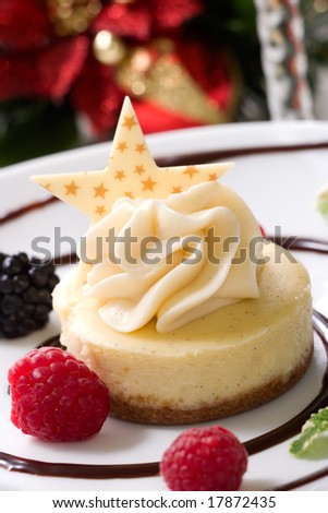 Delicious Vanilla Bean Cheesecake served with fresh raspberries, blackberries and mint. Christmas ornament out of focus in background