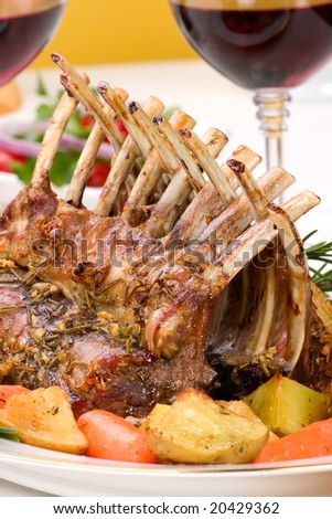 Rack of Lamb (ribs) with Rosemary garlic dressing, garnished with baby carrots, potatoes and rosemary sprigs. Dinner settings.