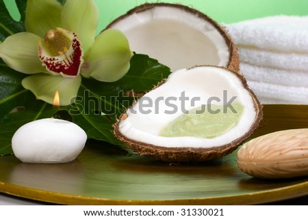 Avocado coconut scrub in coconut shell, orchid flower (Cymbidium sp.), tropical plant, soap and aroma candle. Suited for relaxing and health commercials