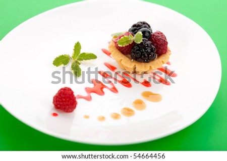Closeup of delicious fresh berry cake garnished with pineapple mint