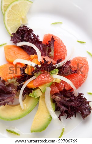 Closeup of papaya, avocado and grapefruit salad with sweet onion and lime wedges