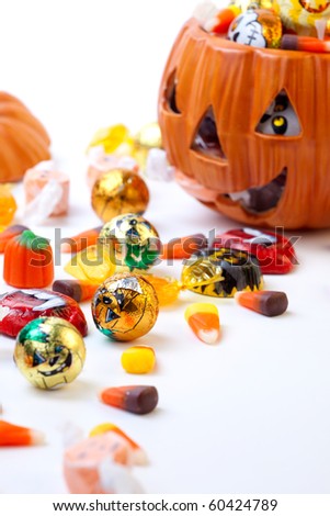 Scatter Halloween candies and orange pumpkin filled by them