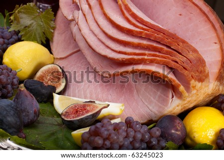 Glazed delicious whole baked honey sliced ham with figs, lemons and champagne grapes.