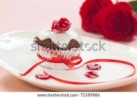 Chocolate muffin garnished with sugar frosted rose and vanilla icing. Valentine\'s day or wedding desert.