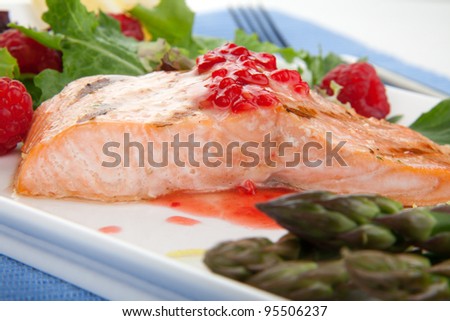 Grilled salmon with raspberry dressing served with asparagus and green salad, healthy meal.