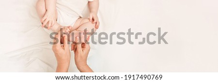 Cute small boy lying at bed. Childhood concept. Light background. Serious child. Copyspace. Stay home. Mockup. Horizontal banner. Foot massage. White clothes