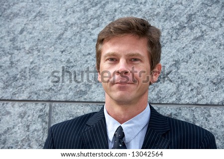 Portrait of man by building wall, smiling, frontal head & shoulders
