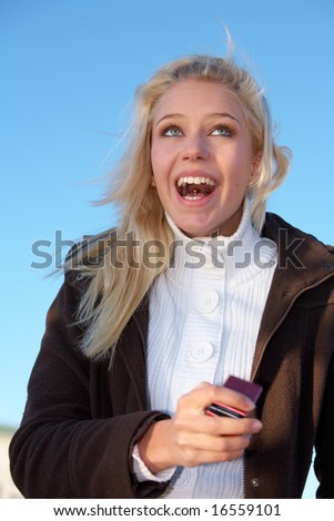 Teenage girl holding mobile phone, laughing