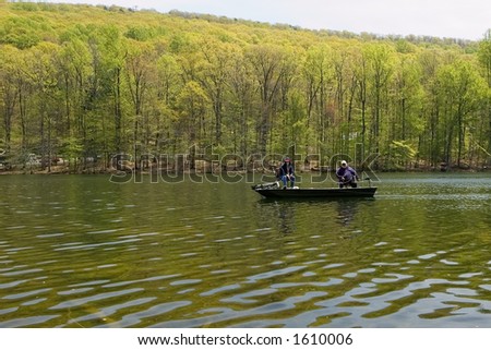 Two fisherman in bass boat at a mountaintop lake.