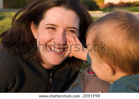 Baby playing game and exploring happy mothers face.
