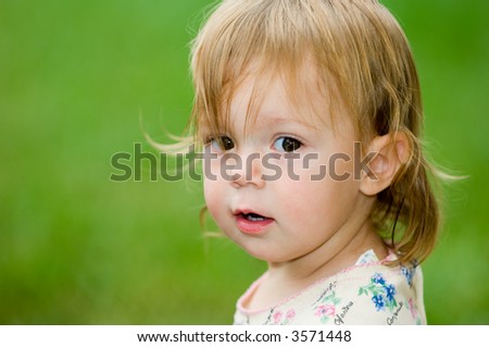 Cute portrait of a toddler girl, making an expression like she has been caught in the act, or is just about to create some mischief.