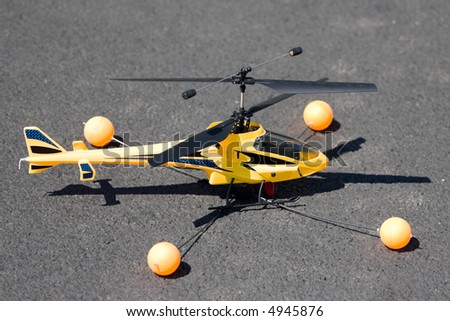 Yellow toy helicopter that really flies and can be controlled from a remote control. Landed on asphalt and ready for takeoff.