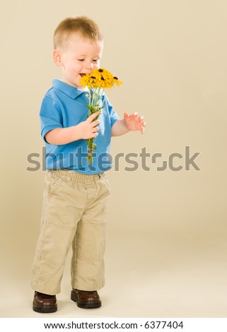 Delighted toddler boy holding a bouquet of yellow Black-Eyed Susan flowers. He is grinning and looking at his gift. These may be a mothers day gift or perhaps he will give them to a lucky little girl.