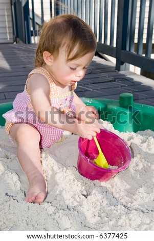 For babies aged one to two, everything is a learning experience. This little girl is very curious and busy as she plays in her sandbox with a shovel and pale.