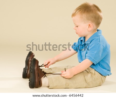 Two year old boy concentrating on tying (or untying) his shoes.