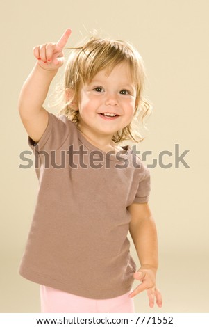 Adorable baby girl holding up pointer finger. How old are you? I am one! Neutral color palette.