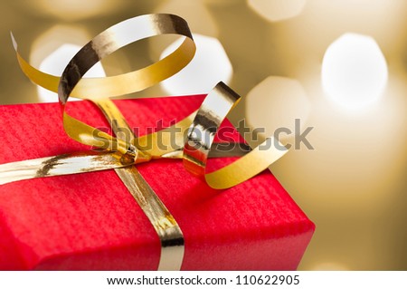 Photo of red and gold gift box with out of focus lights on a golden background