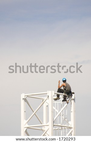 Construction worker sits on top of crane tower