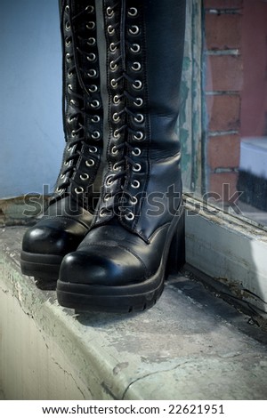 Goth punk knee-high fashion boots standing on old window sill.
