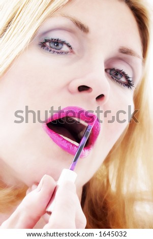 Close-up headshot of a gorgeous woman applying lipstick to her lips.