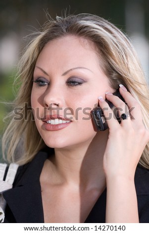 Portrait head shot of a young business woman smiling and talking on a cell phone.