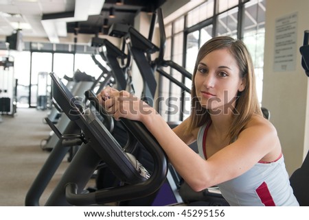 Woman working out on a stationary cycle machine in a fitness club.