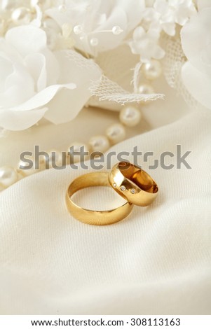 two wedding rings, pearls and flowers