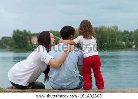 Father, mother and daughter - family on the river bank