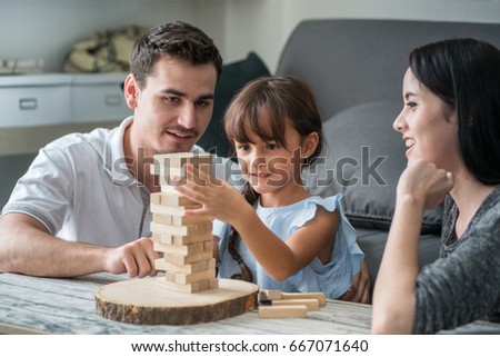 Similar – Image, Stock Photo Excited girl playing jenga game with her mom in play room. Girl removing one block from stack and placing it on top of tower. Game of skill and fun. Family time