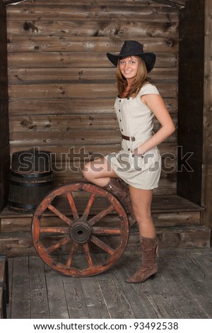 CowGirl with a ancient cart wheel standing in old depot