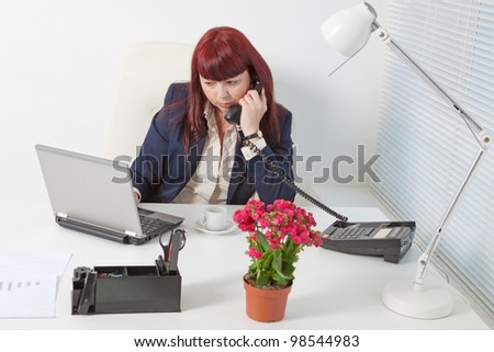 Confident business woman speaks by phone  in a comfortable modern office