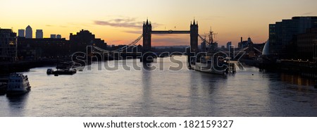 LONDON, UK - MARCH 16TH 2014: A panoramic view of a London Sunrise leaving the the sights of Tower Bridge, HMS Belfast and Docklands in silhouette on 16th March 2014.
