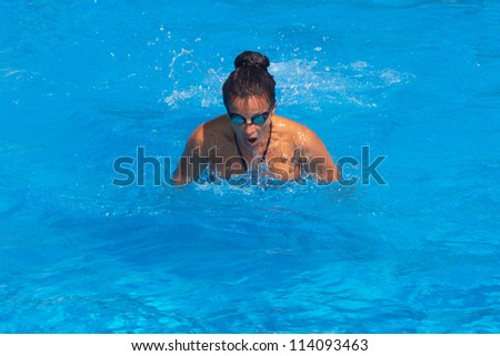 Pretty young female swimmer posing in swimming pool