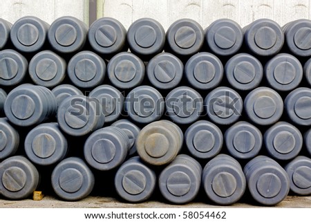 Big pile of gray plastic barrels in factory