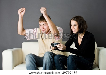Photo of a guy and a girl, sitting on sofa and playing