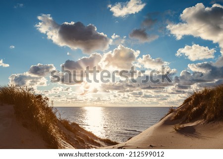 Sunset landscape of the shore of Baltic sea with fleecy clouds,sun rays and sand dunes