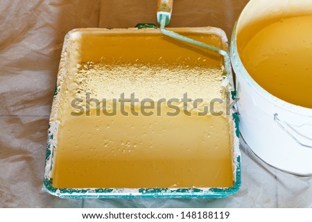 plastic paint tray with painter roller brush and bucket with yellow paint